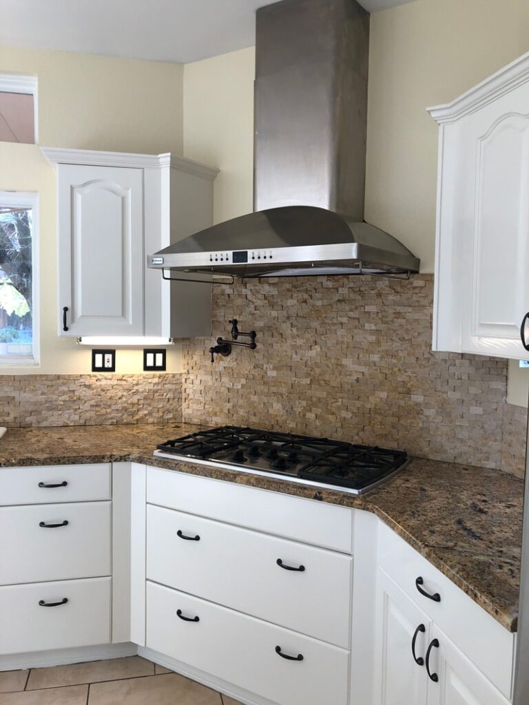 Painted white kitchen cabinets under a range hood