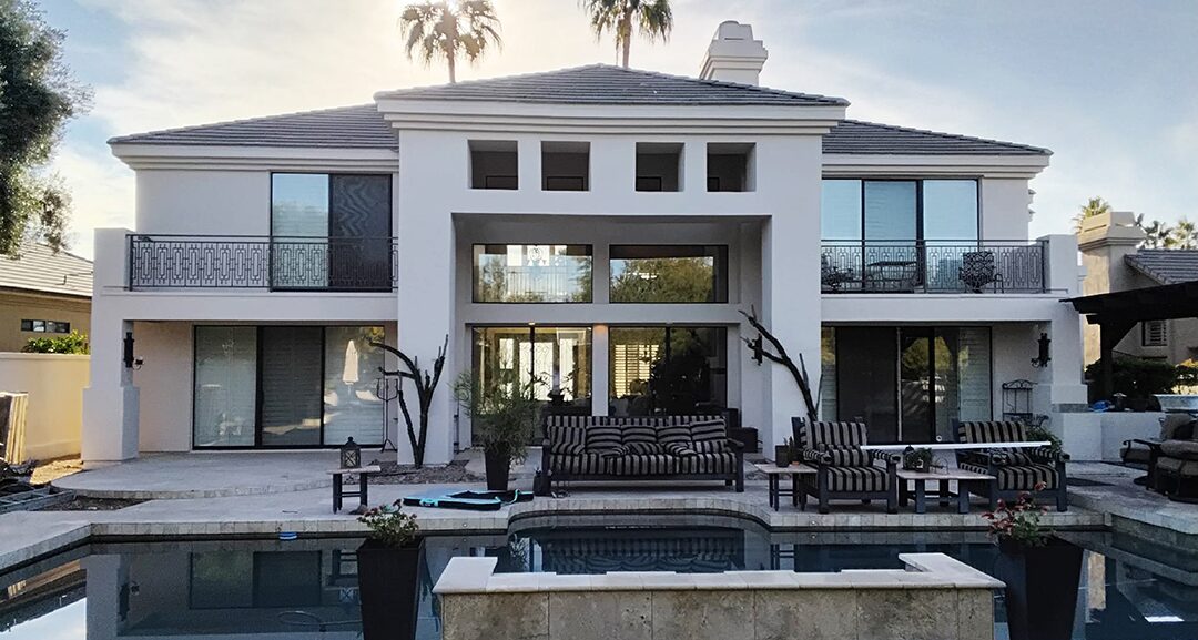 After painting: the same two-story stucco home in white, viewed across the pool