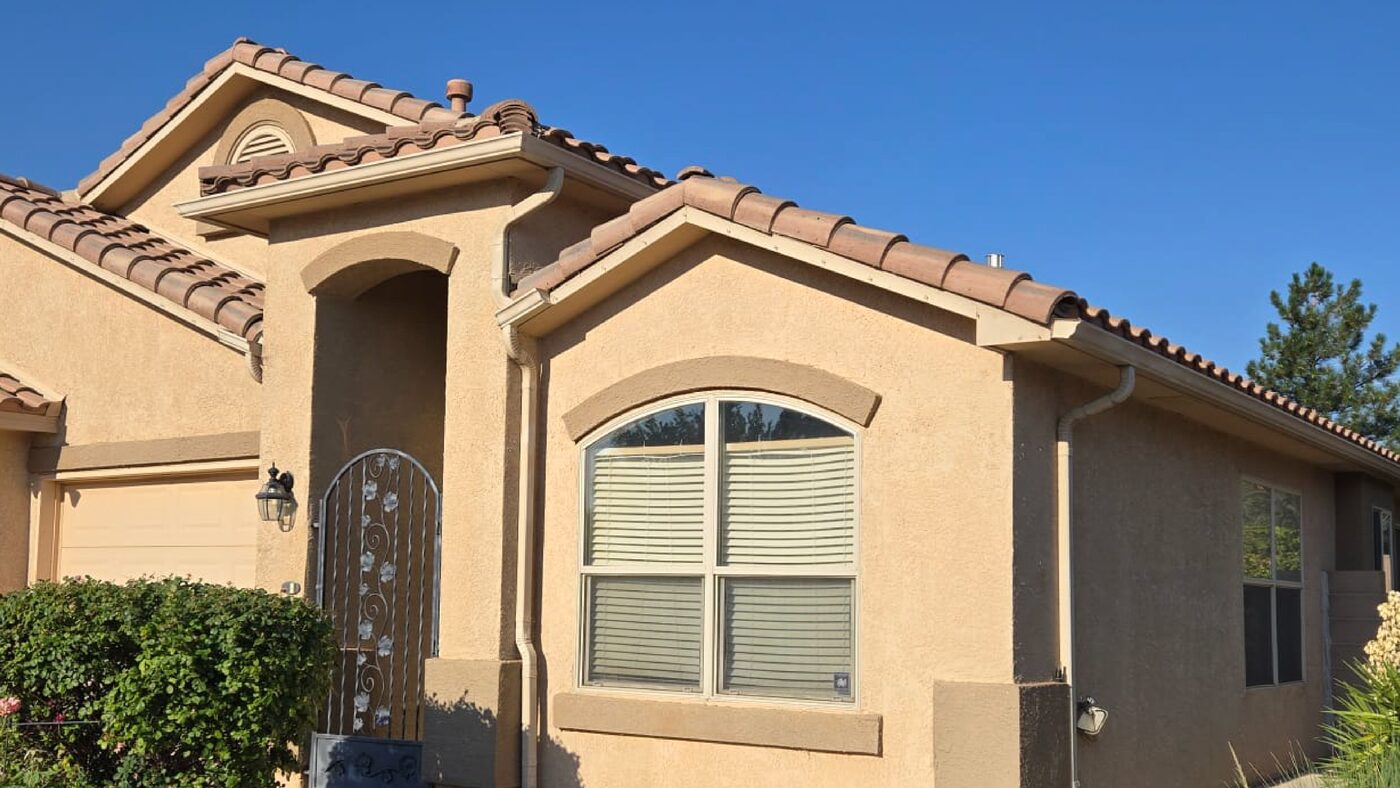 Tan stucco home with a red clay tile roof and arched front window