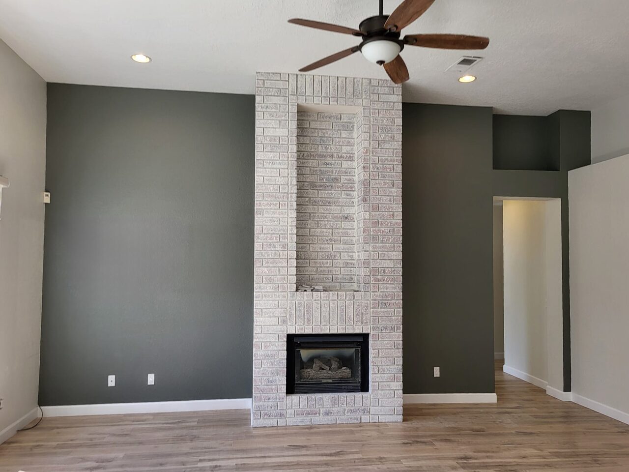Living room with a dark grey accent wall and a whitewashed brick fireplace