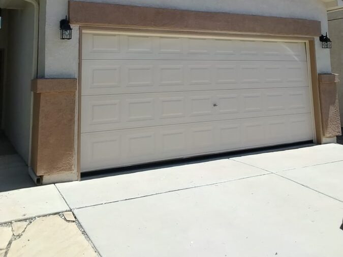 Two-car garage with a cream garage door and tan stucco trim